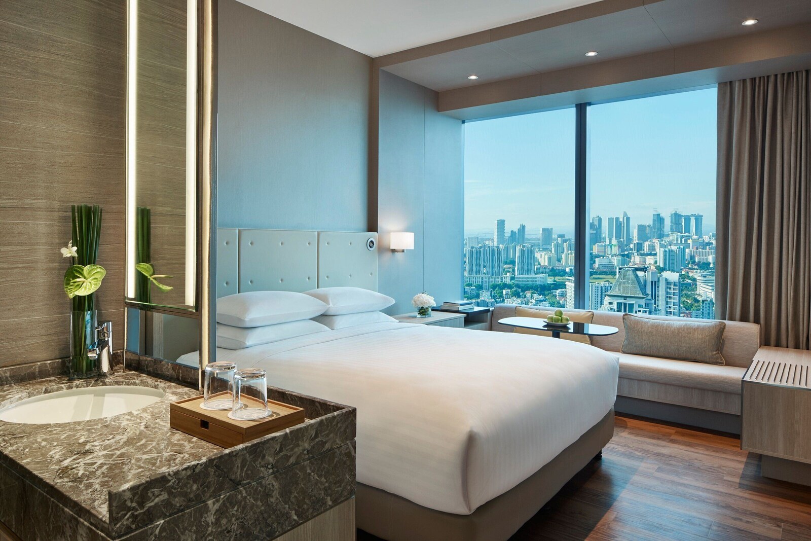 A modern hotel room with a large bed, a bathroom with a marble sink, and a city view through large windows. - Courtyard by Marriott Singapore Novena (Singapore)